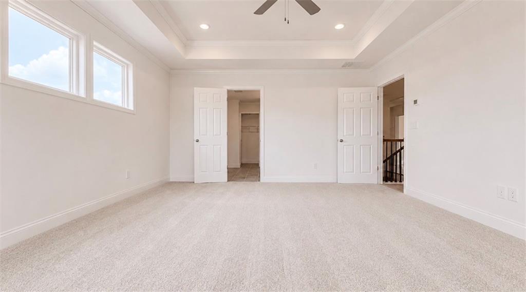 Spacious bedroom with tray ceiling and walk-in closet in The Hickory C floor plan at Wehunt Meadows, Hoschton, Georgia.