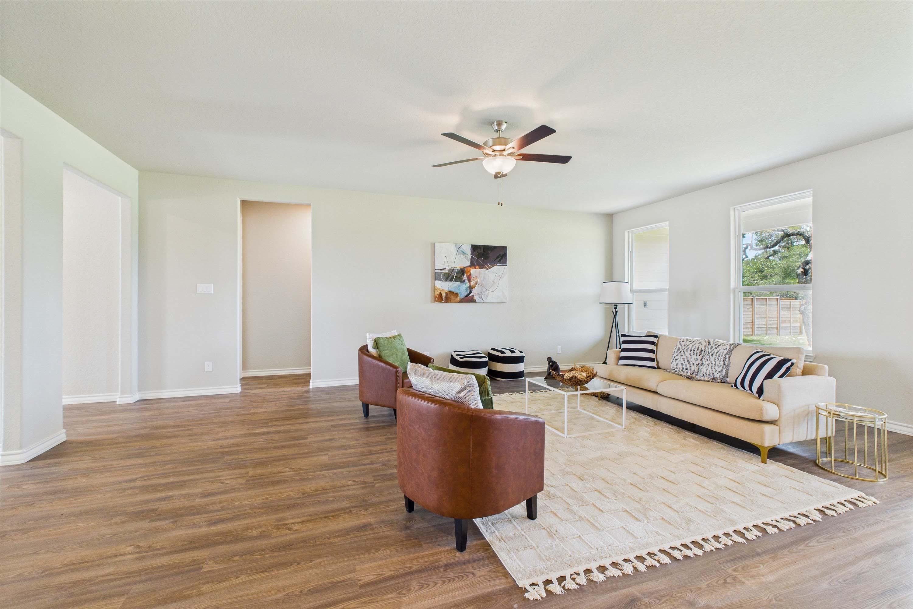 Spacious open-concept living area in The Foster featuring light-toned flooring, modern furniture, and natural lighting.