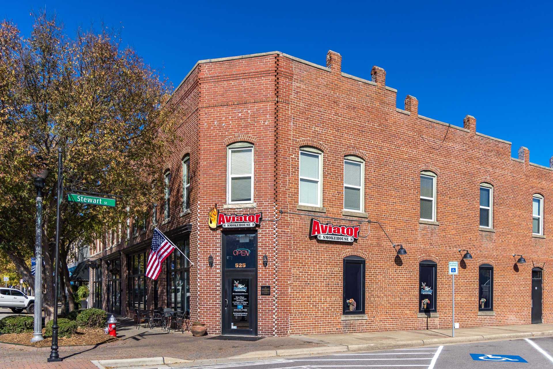 Charming red brick corner building with Avatar signage, American flag, and autumn trees in Fuquay-Varina NC near Prince Place