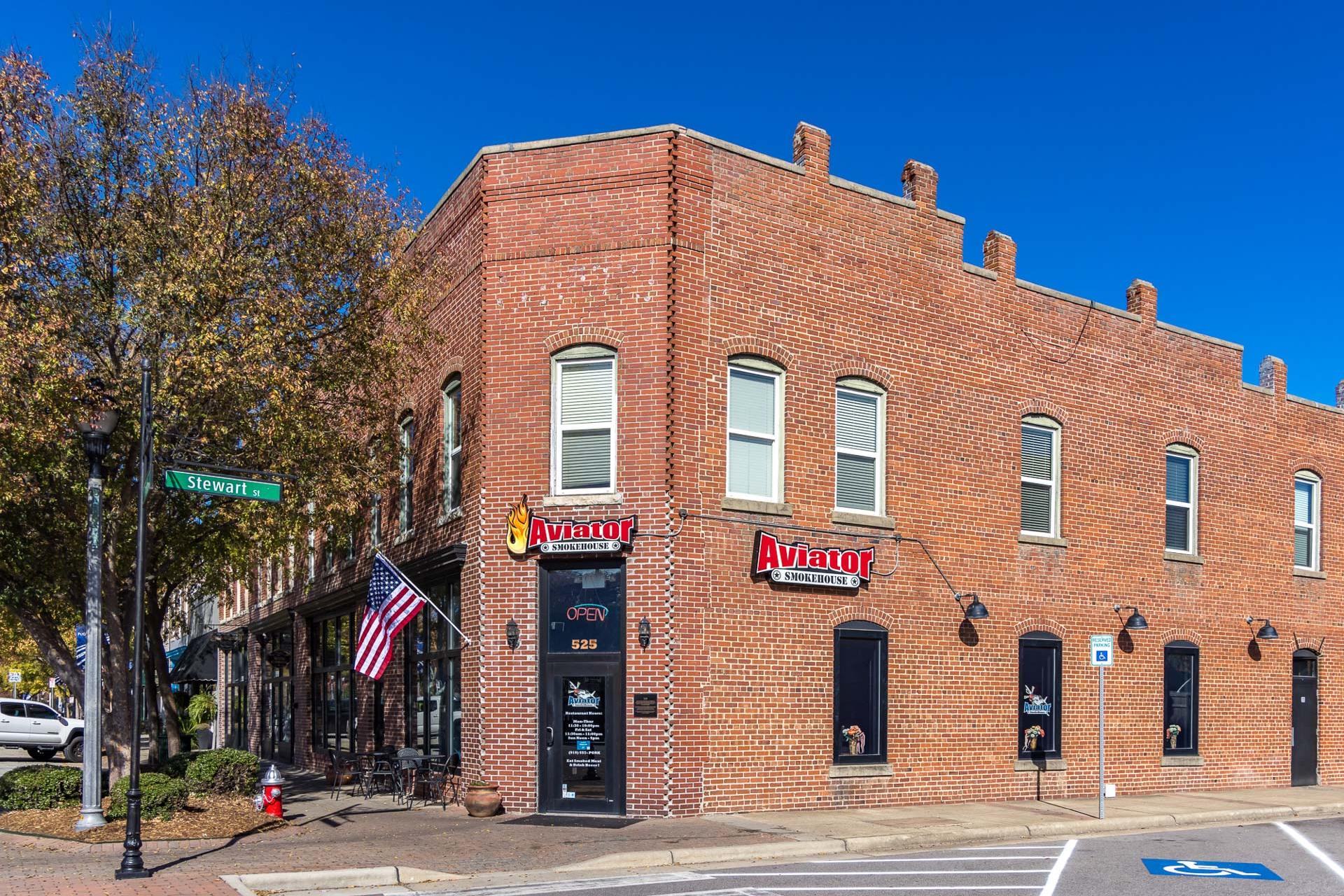 Charming red brick corner building with Avatar signage, American flag, and autumn trees in Fuquay-Varina NC near Prince Place