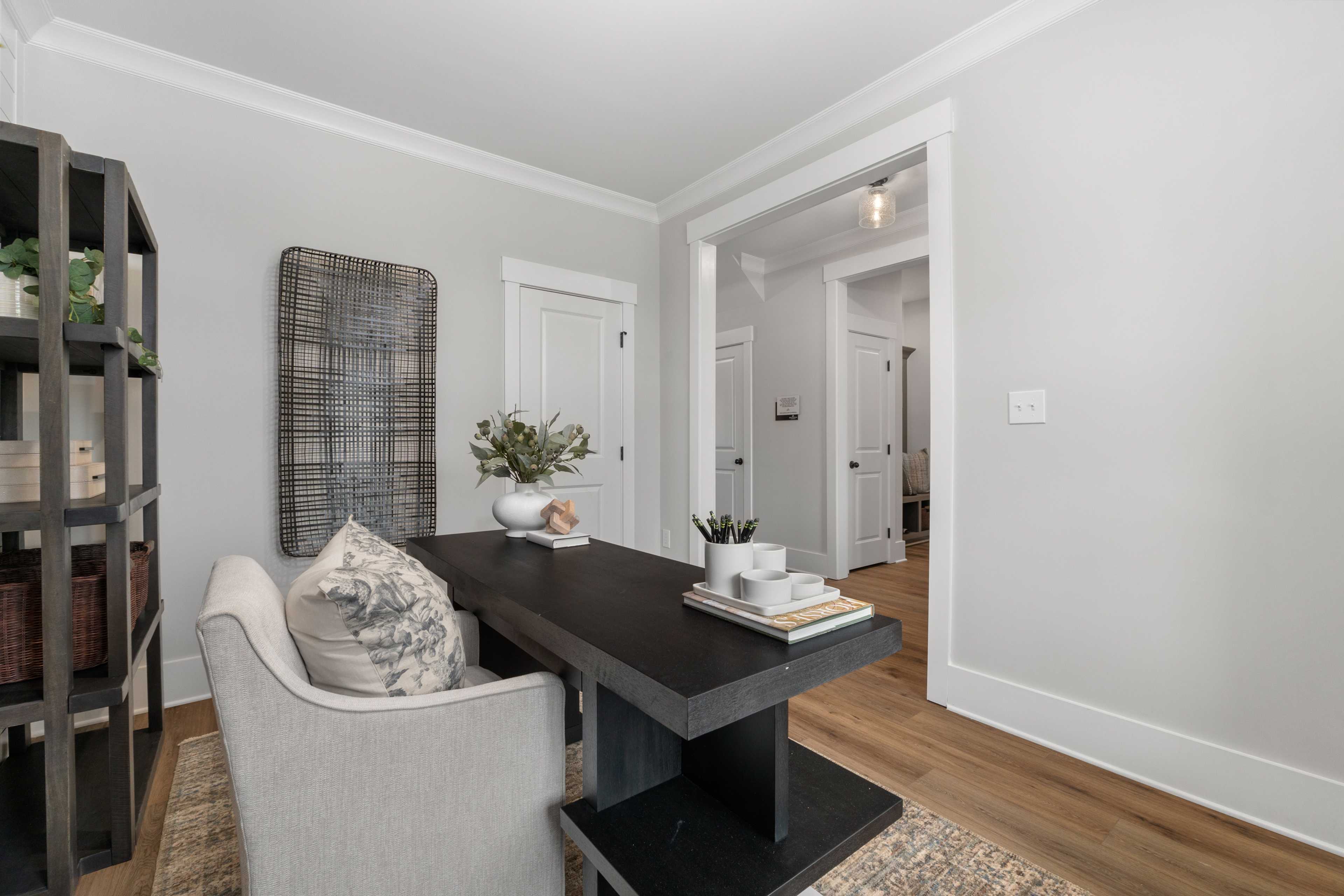 Spacious home office in Kendall Farms Toney Alabama with black desk gray armchair bookshelves and hardwood floors