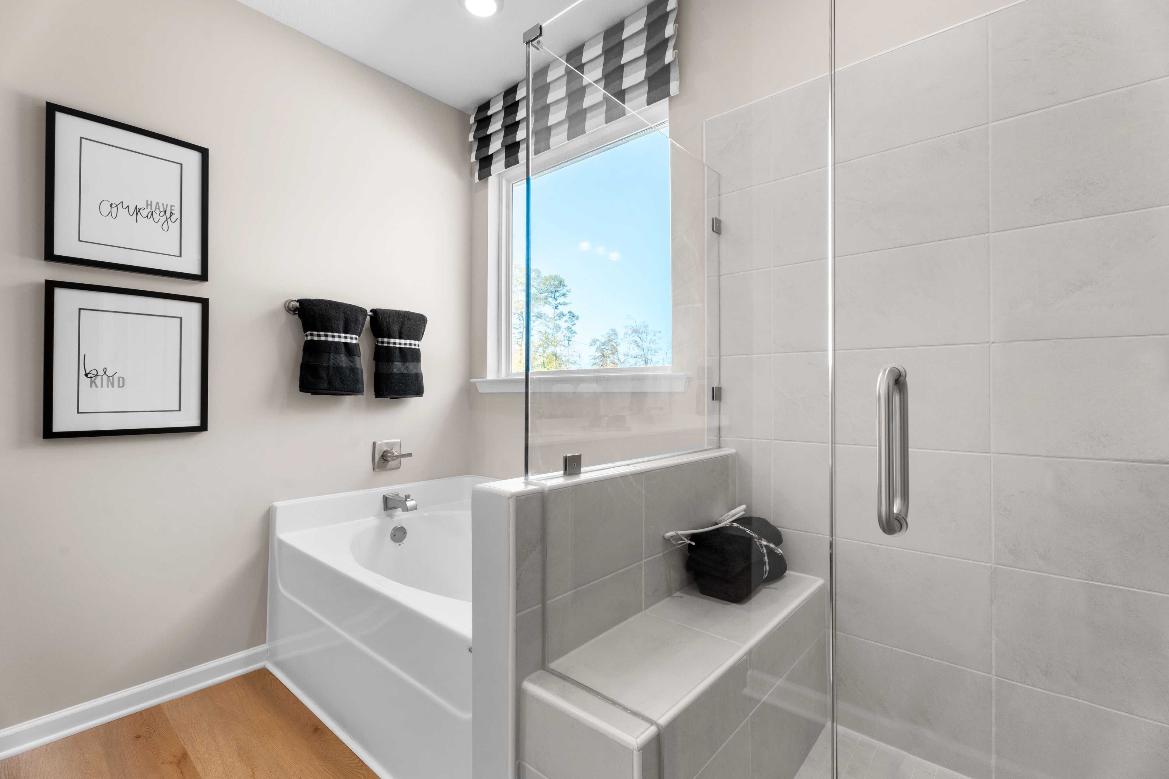 Spacious master bathroom in Silver Oak Cusseta Alabama with white tub glass shower checkered valance by Evermore Homes