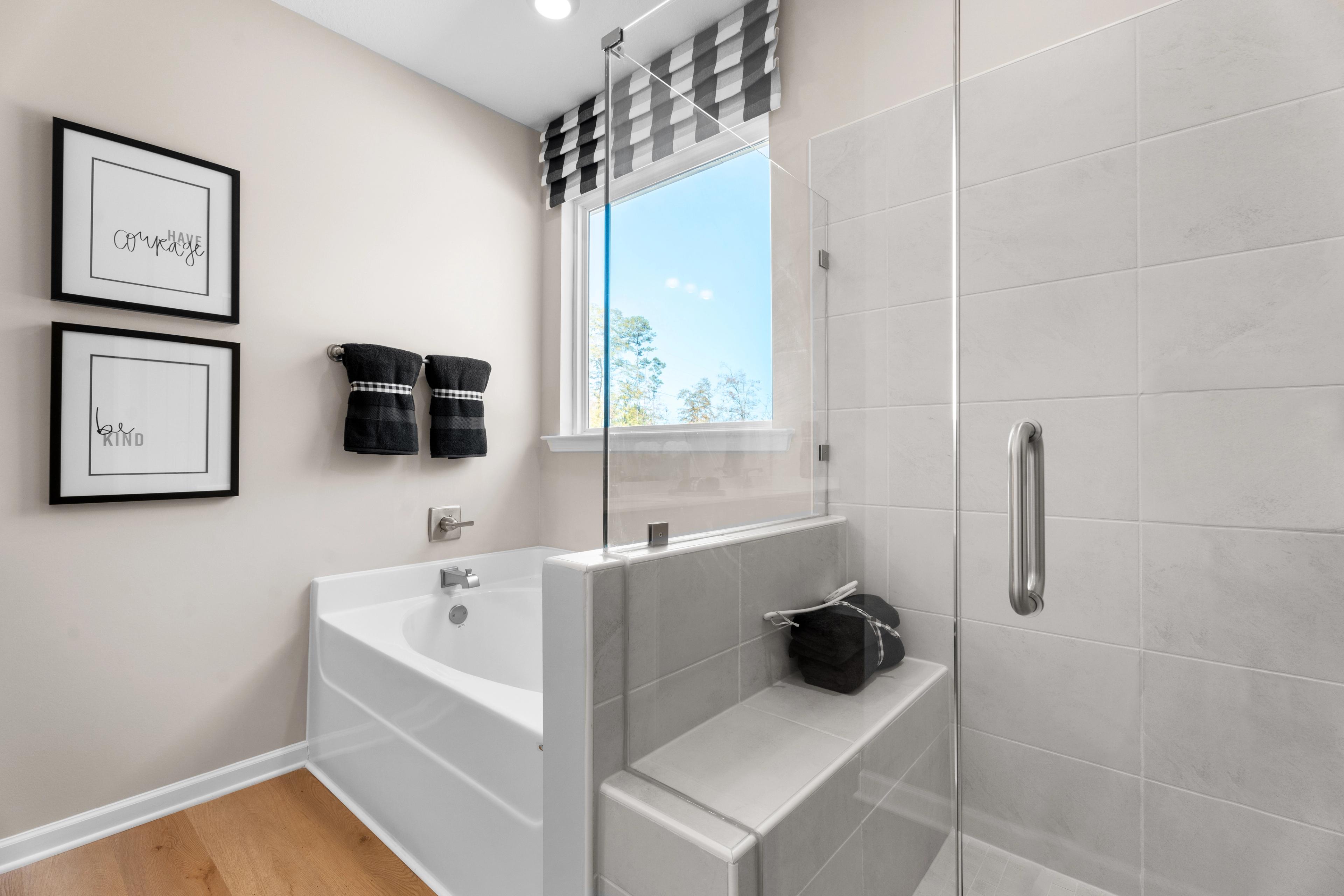 Spacious master bathroom in Silver Oak Cusseta Alabama with white tub glass shower checkered valance by Evermore Homes