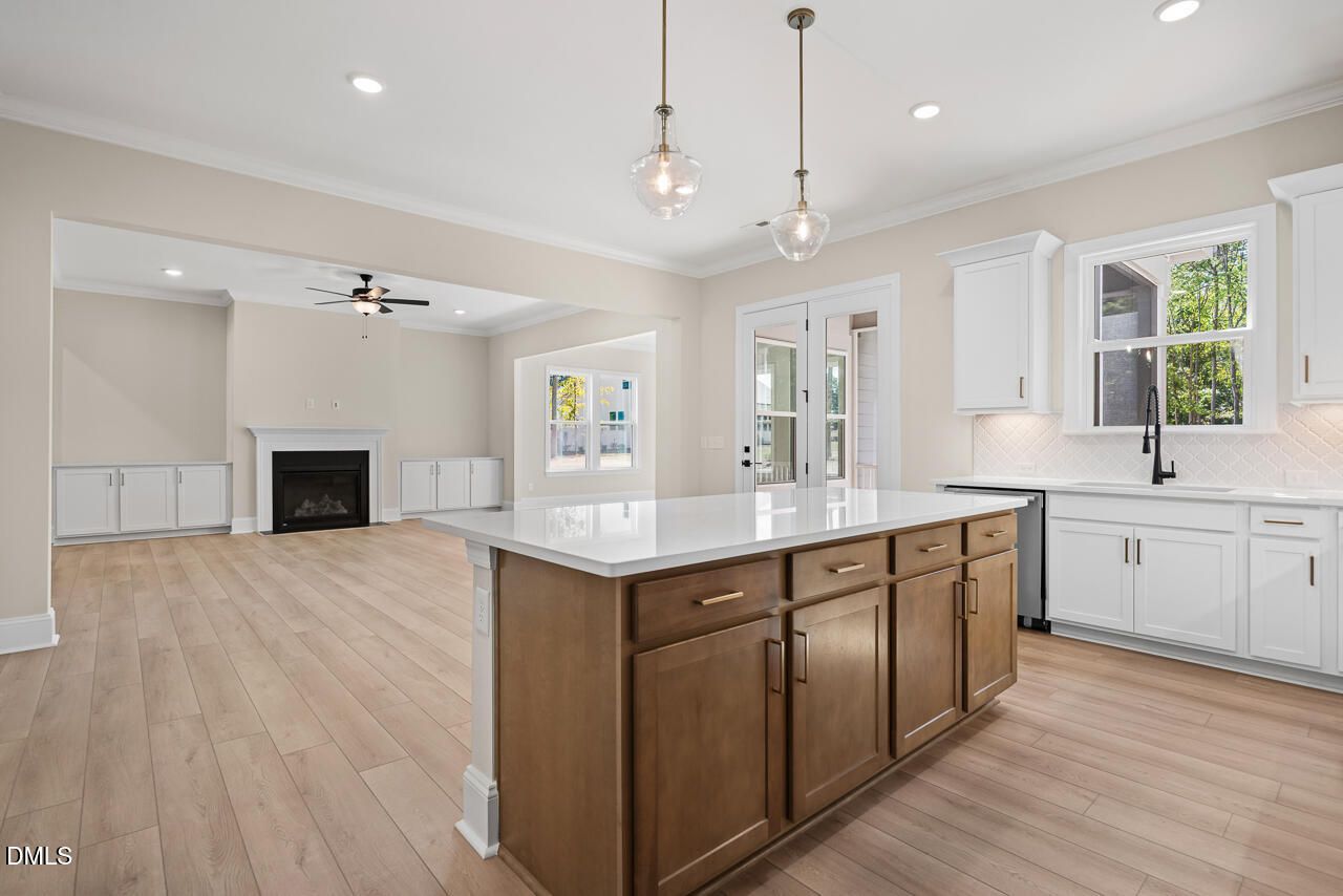 Open-concept kitchen with wood island, white cabinetry, and fireplace in Davidson Homes Crawford D plan, Wake Forest, NC