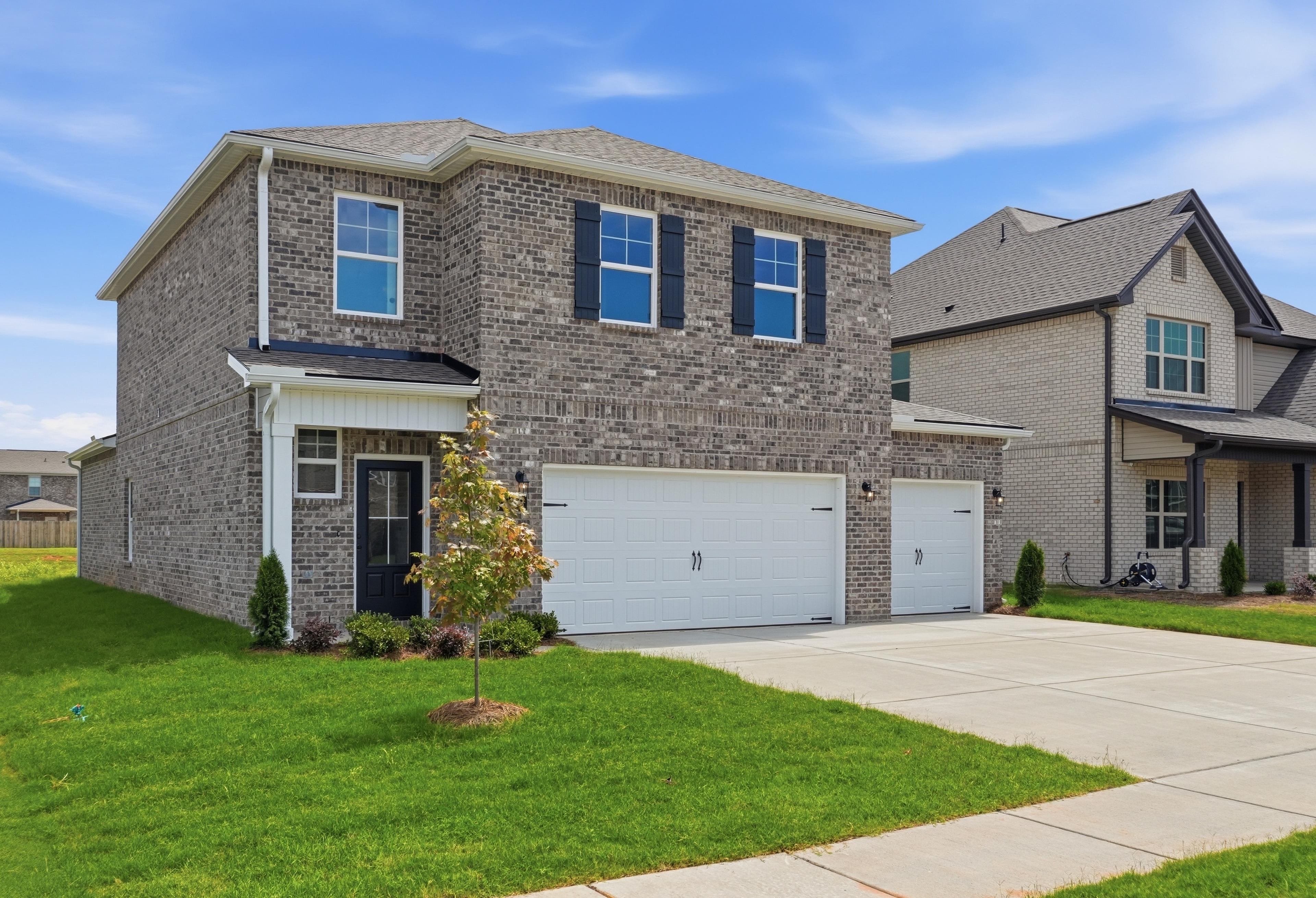 Two-story brick exterior of The Meadowbrook A by Davidson Homes featuring a 3-car garage in Meridianville, Alabama.