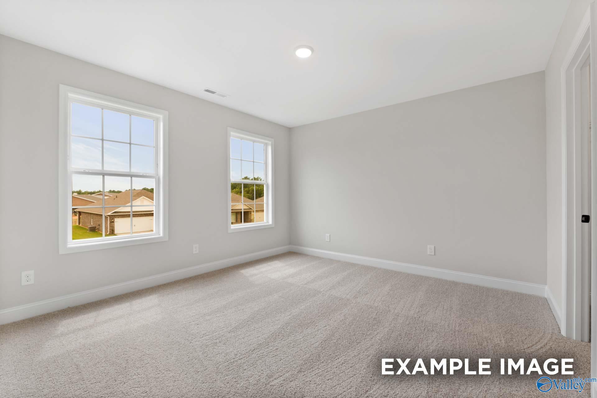 Bright, carpeted bedroom with neutral walls in The Shelby B floor plan by Davidson Homes in Jaguar Hills, Huntsville, AL.
