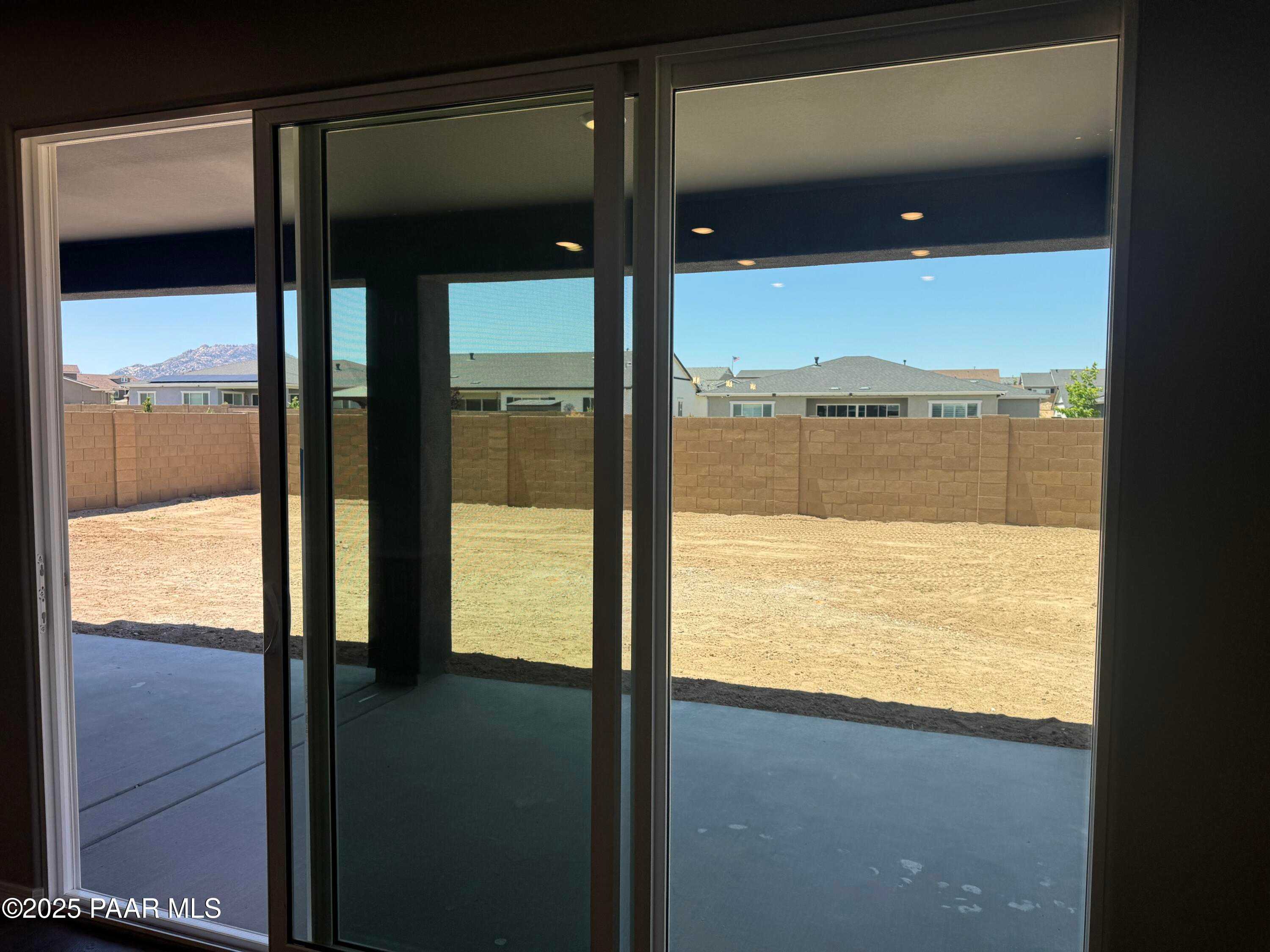 Sliding glass doors to covered patio and dirt backyard with mountain views in Davidson Homes Durango II A, Prescott, Arizona