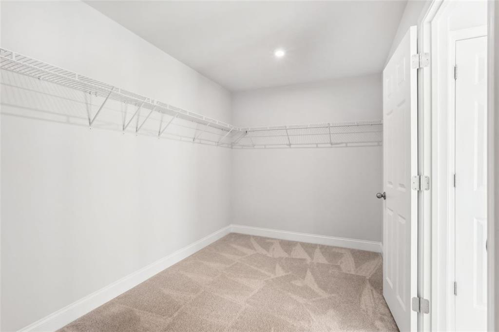 Spacious walk-in closet with wire shelving, beige carpet, and double doors in Davidson Homes The Hickory C, Hoschton, GA