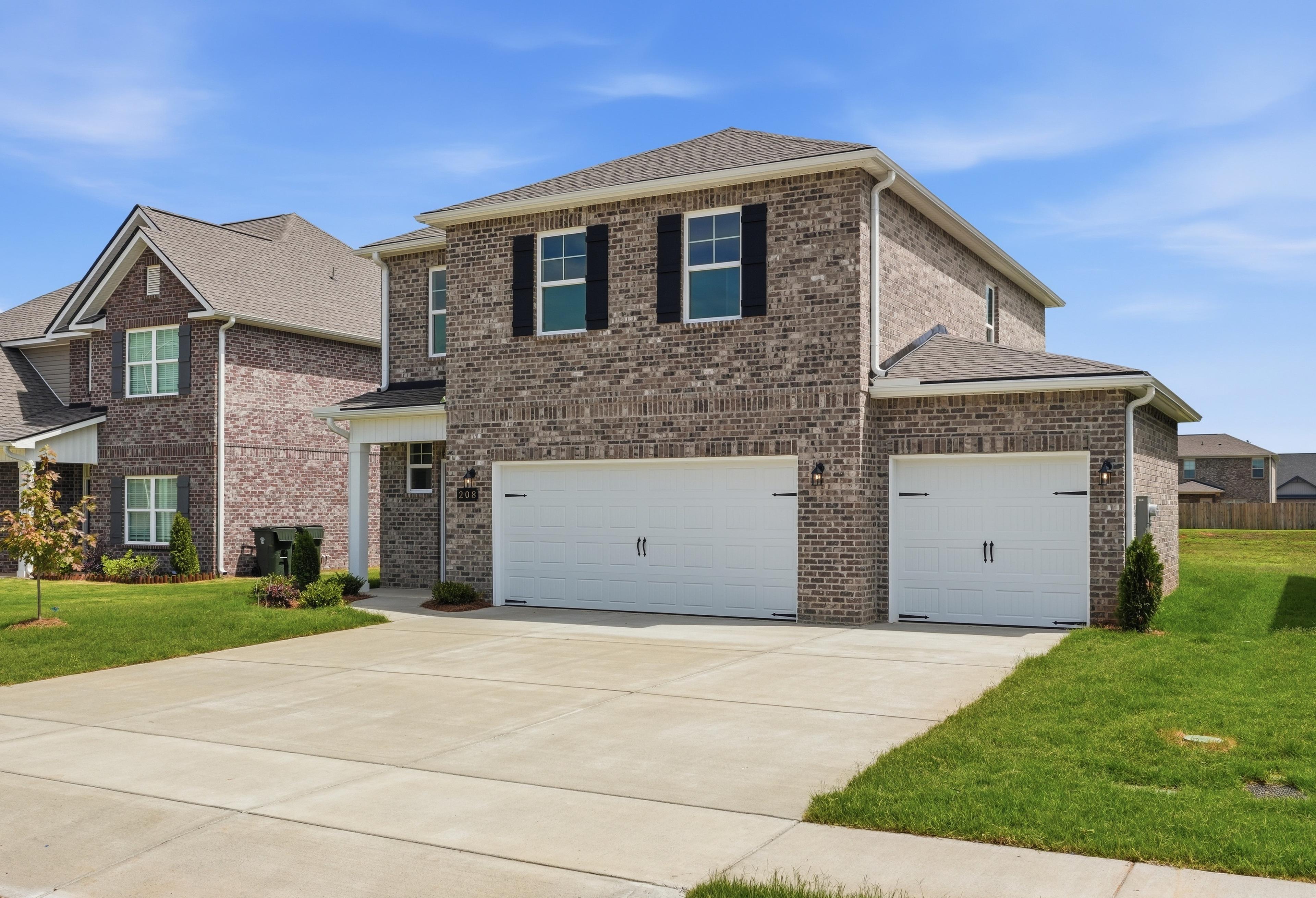 Two-story brick exterior of The Meadowbrook A by Davidson Homes featuring a spacious 3-car garage in Meridianville, Alabama.