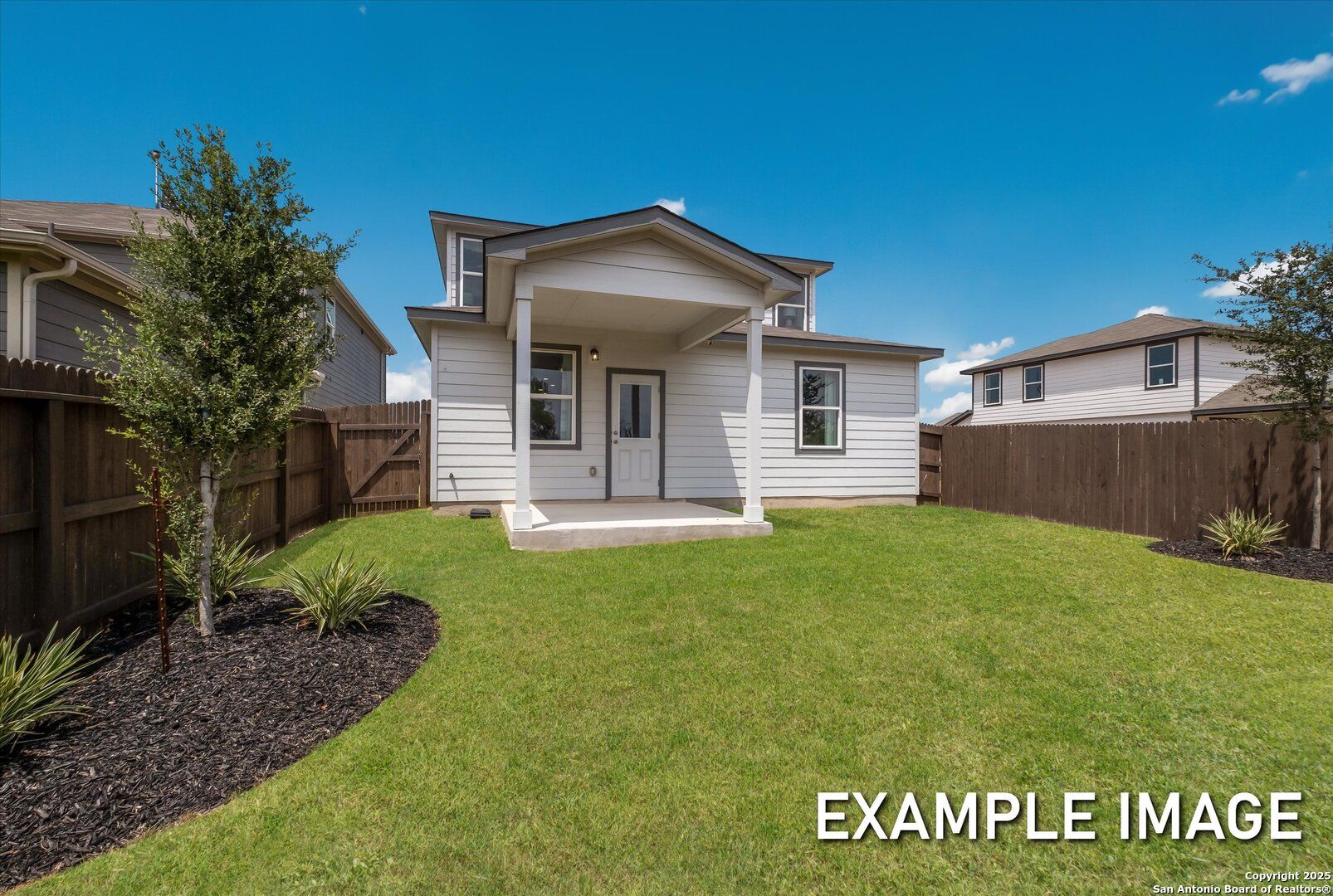 Covered back patio with white siding home, lush green lawn, and privacy fence in Davidson Homes The Sabine C, Agave, San Antonio