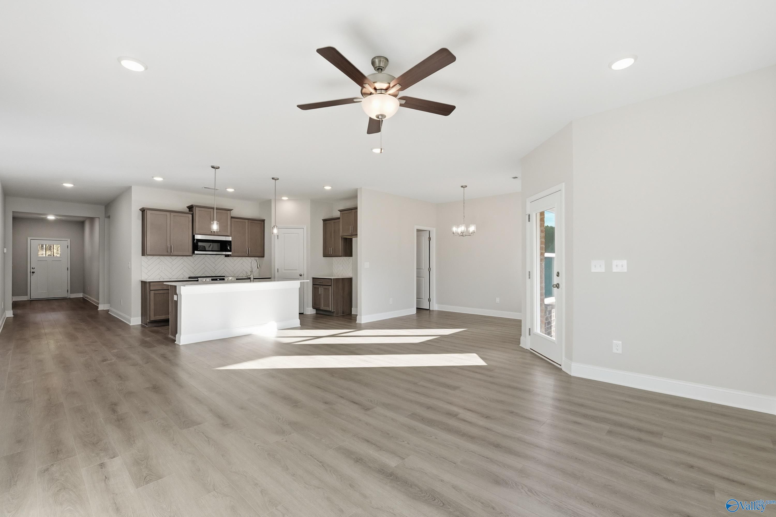 Open-concept living room with ceiling fan, kitchen island, hardwood floors in Davidson Homes The Daphne C, Arab, Alabama