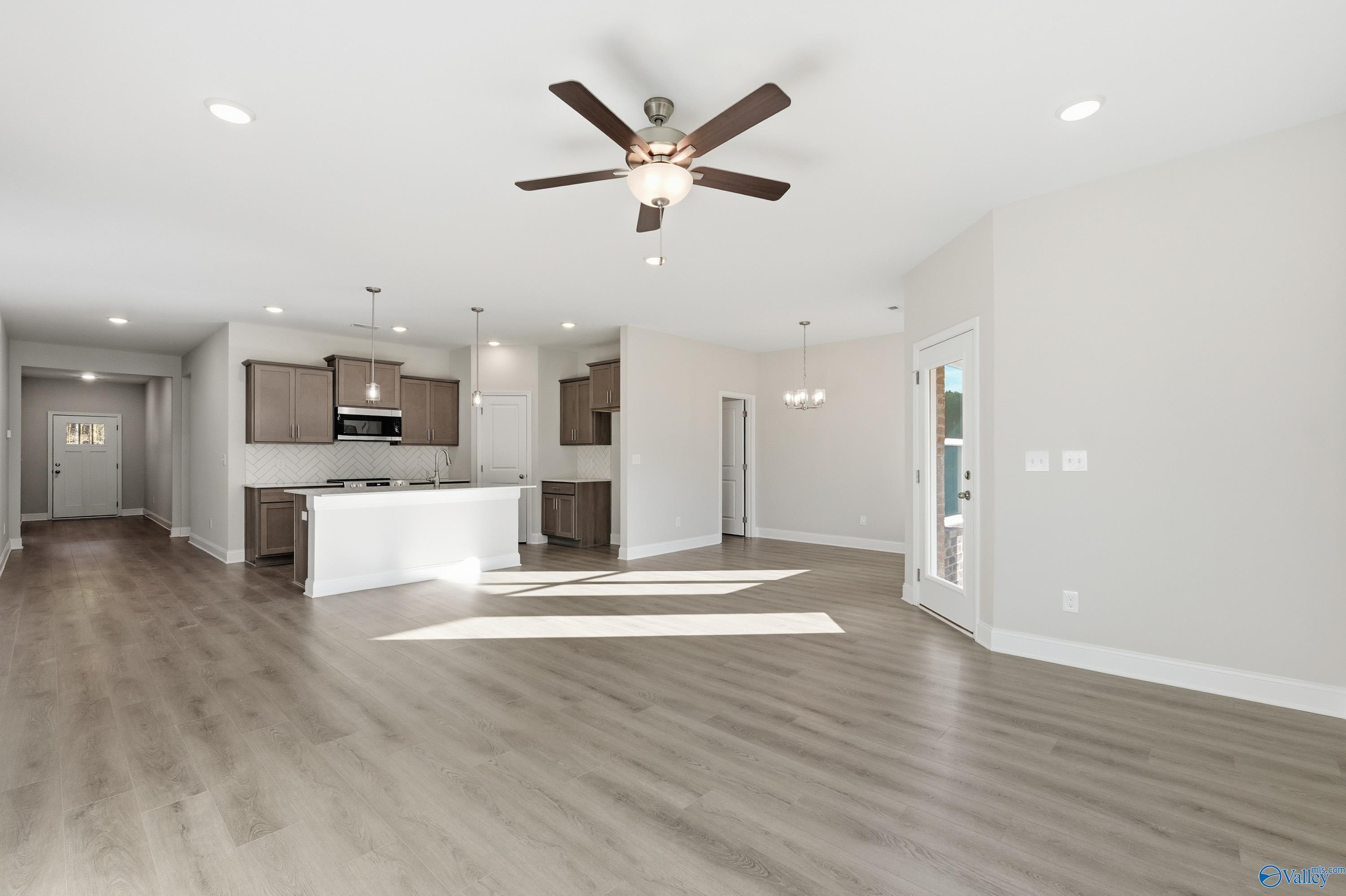 Open-concept living room with ceiling fan, kitchen island, hardwood floors in Davidson Homes The Daphne C, Arab, Alabama