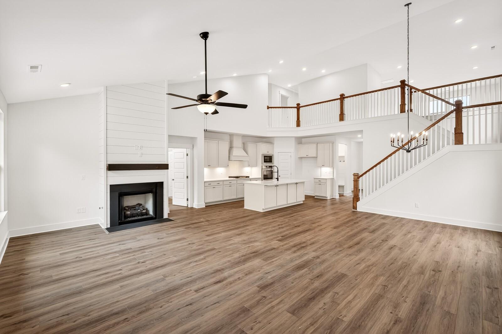 Spacious open-concept great room with shiplap fireplace, kitchen island, and staircase in Davidson Homes Ridgeport C, Gallatin, TN