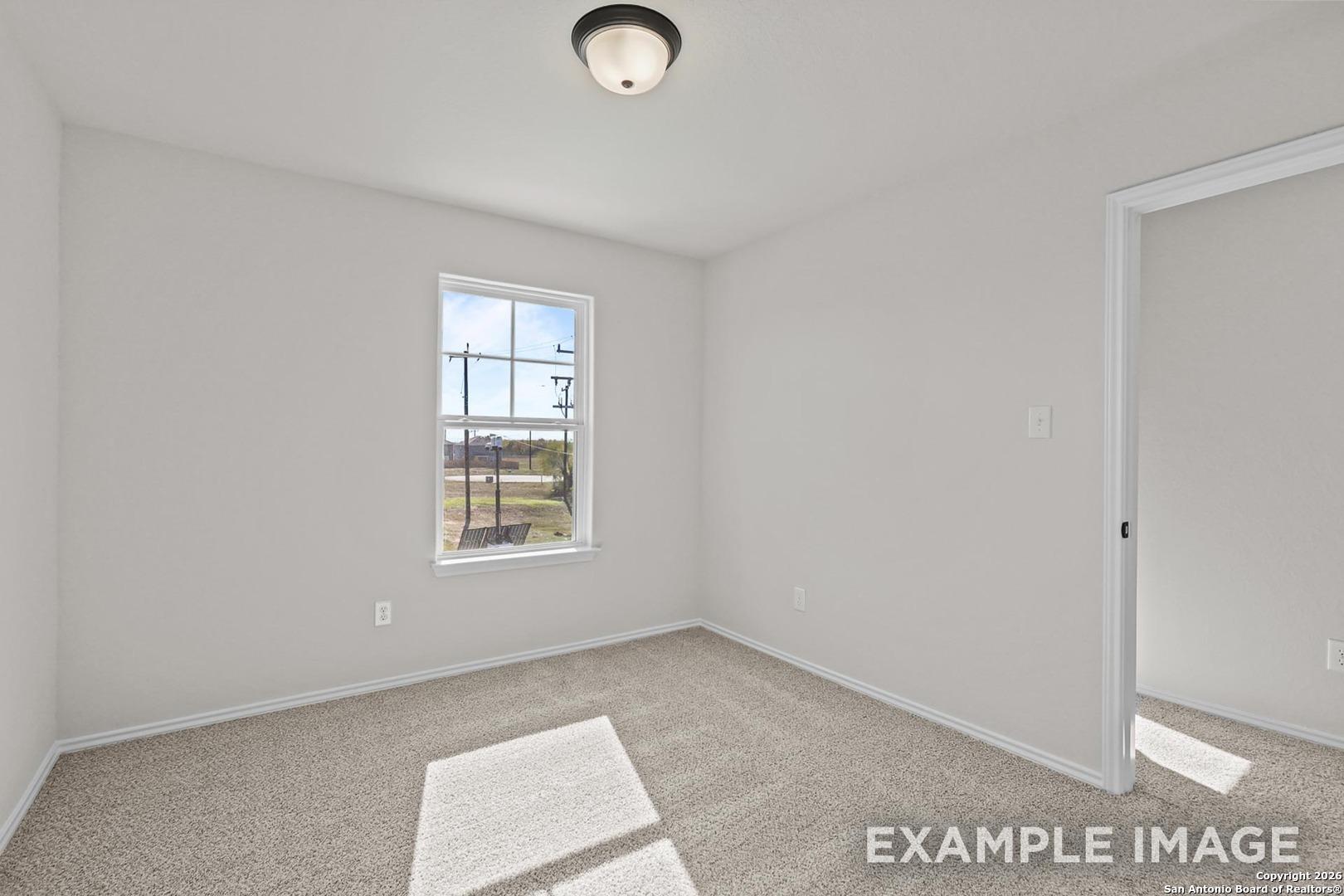 Bright bedroom with neutral walls, carpet floor, large window, and ceiling light in Davidson Homes The Trinity B, San Antonio, Texas