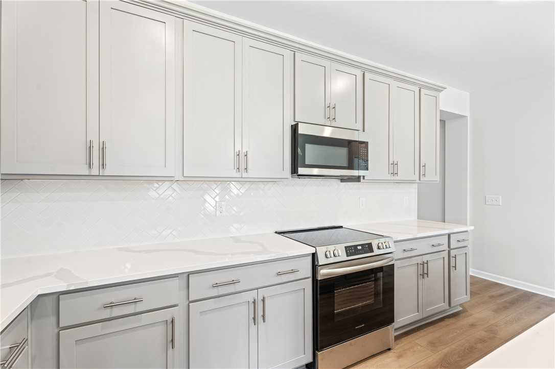Modern white shaker kitchen with quartz countertops, subway tile backsplash, stainless appliances in Davidson Homes Luna B, Opelika AL