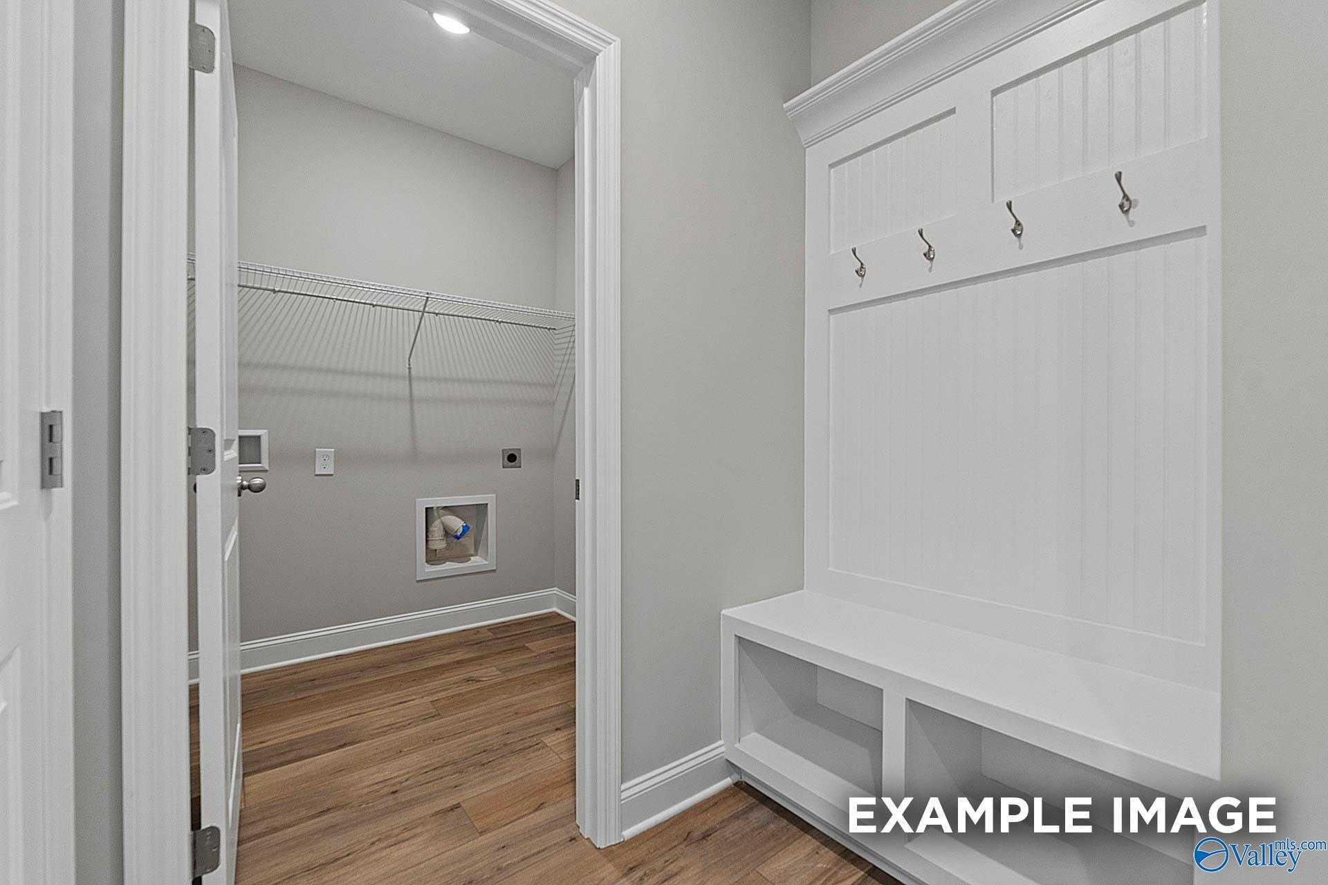 Functional mudroom with built-in bench, coat hooks, wire shelving, and laundry area in Davidson Homes The Franklin E, Hazel Green