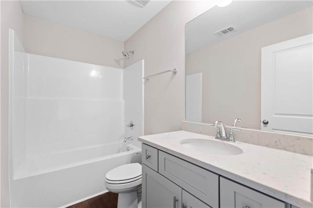 Modern bathroom with white tub, gray shaker vanity, quartz countertop in Davidson Homes The Washington, Phenix City, AL