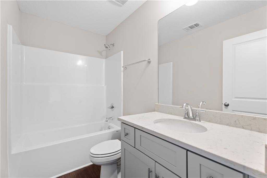 Modern bathroom with white tub, gray shaker vanity, quartz countertop in Davidson Homes The Washington, Phenix City, AL