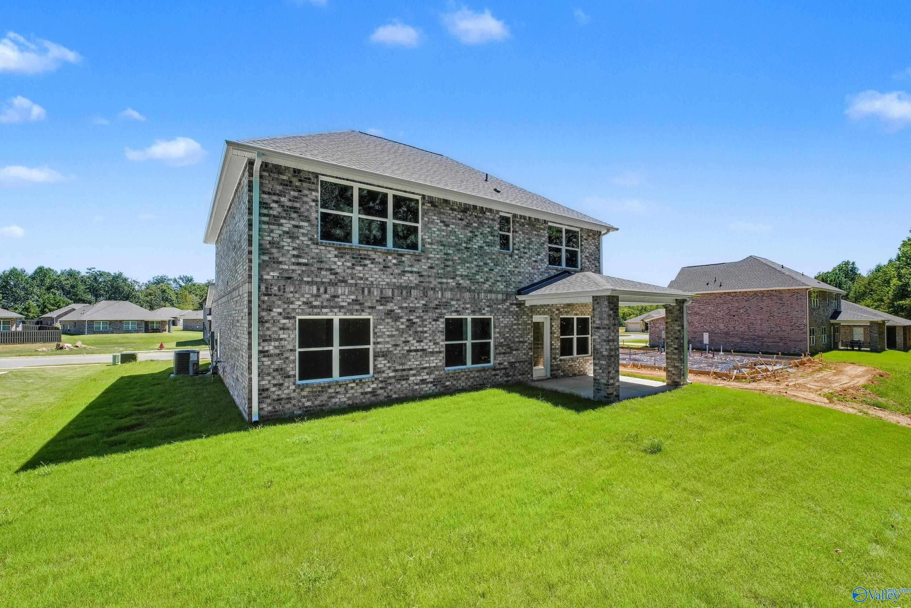 Two-story brick Shelby A home by Davidson Homes with two-car garage, covered porch, and lush green lawn in The Highlands, Arab, Alabama