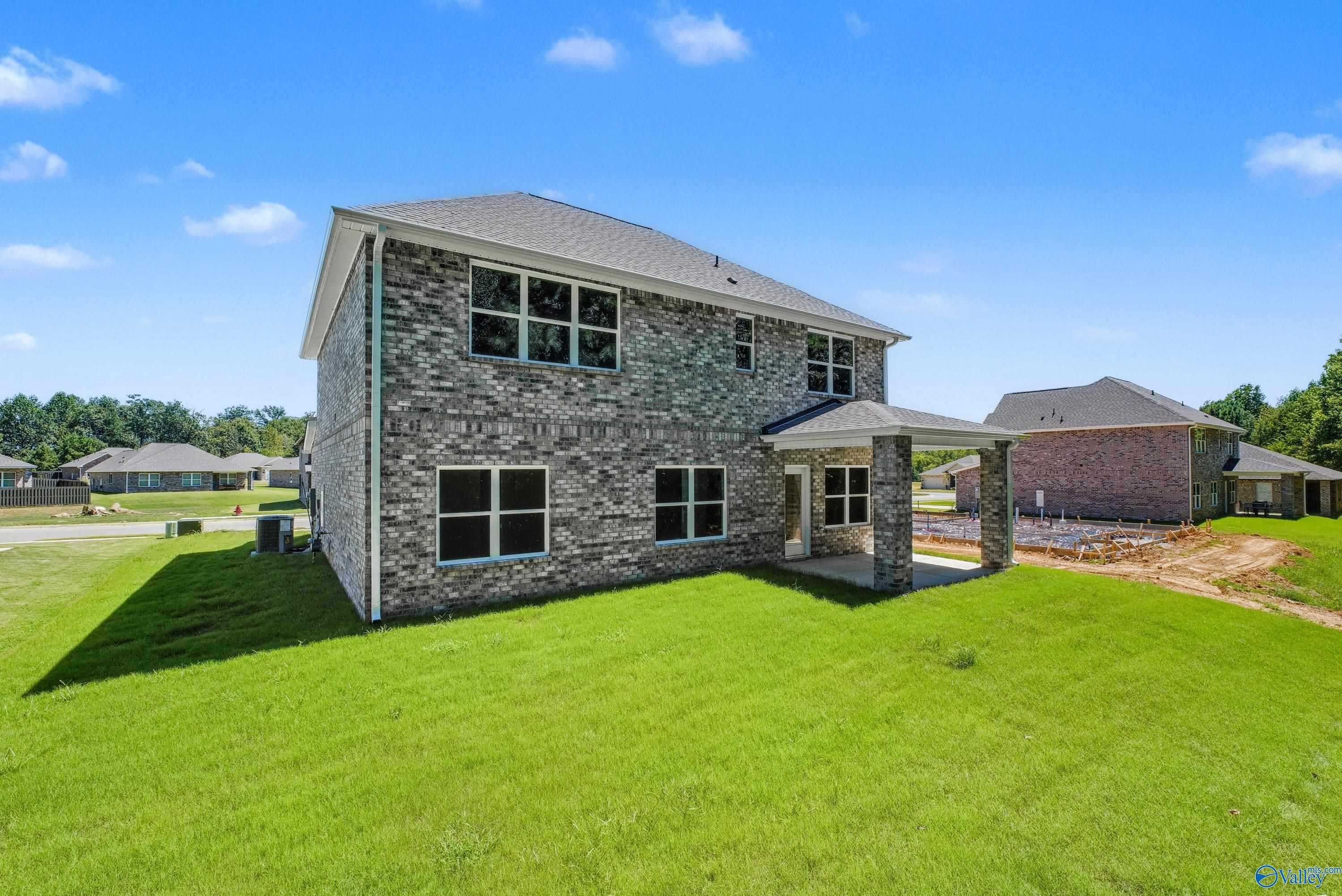 Two-story brick Shelby A home by Davidson Homes with two-car garage, covered porch, and lush green lawn in The Highlands, Arab, Alabama