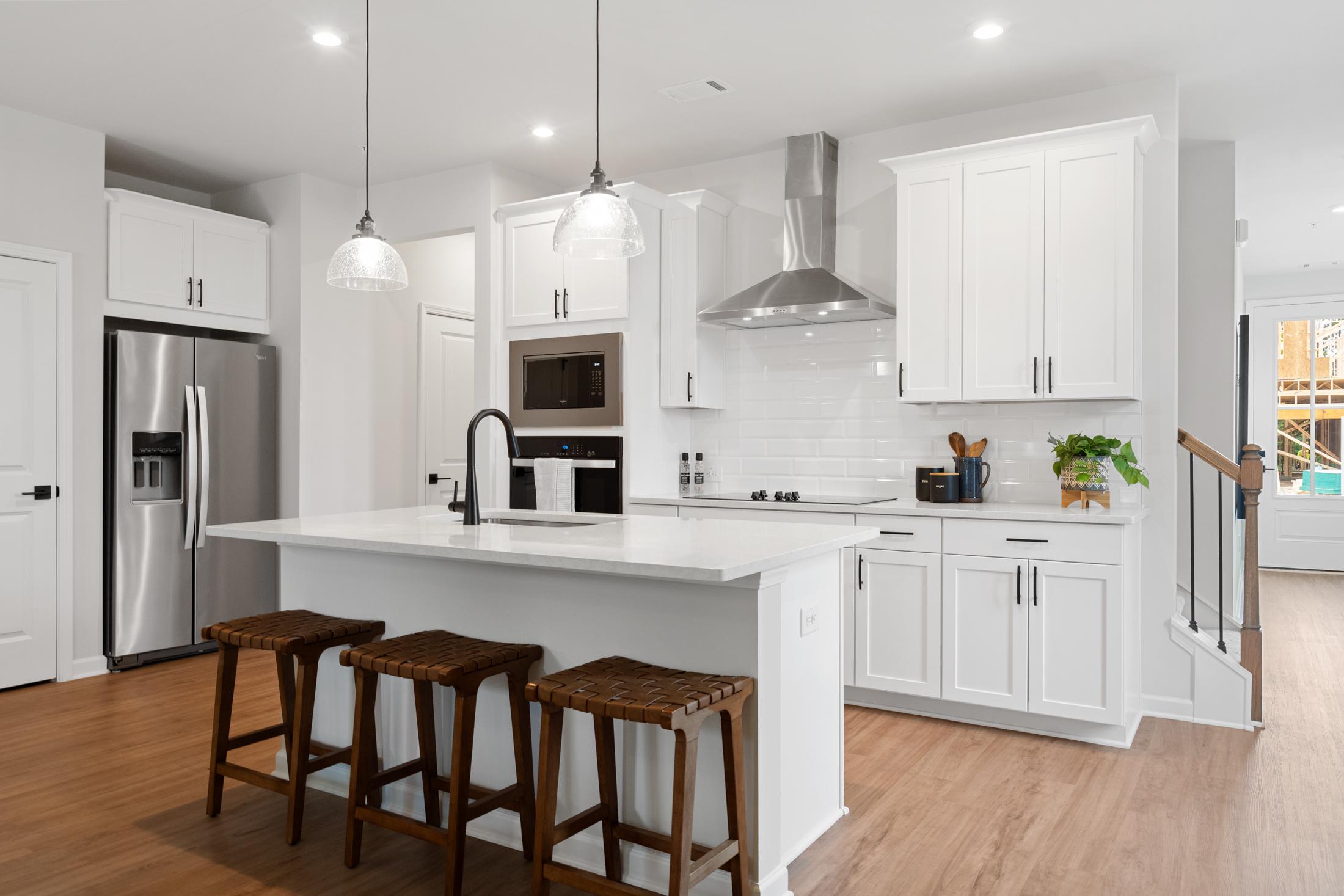 Spacious white kitchen at Rosehill Townhomes in Marietta GA with central island, stainless steel appliances, and hardwood floors