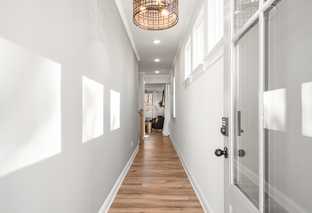 Bright hallway in The Washington H townhome, Marietta GA, with light gray walls, hardwood floors, rattan pendant light, and clerestory windows