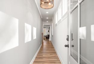 Bright hallway in The Washington H townhome, Marietta GA, with light gray walls, hardwood floors, rattan pendant light, and clerestory windows