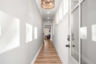 Bright hallway in The Washington H townhome, Marietta GA, with light gray walls, hardwood floors, rattan pendant light, and clerestory windows