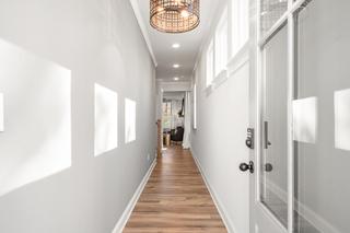Bright hallway in The Washington H townhome, Marietta GA, with light gray walls, hardwood floors, rattan pendant light, and clerestory windows