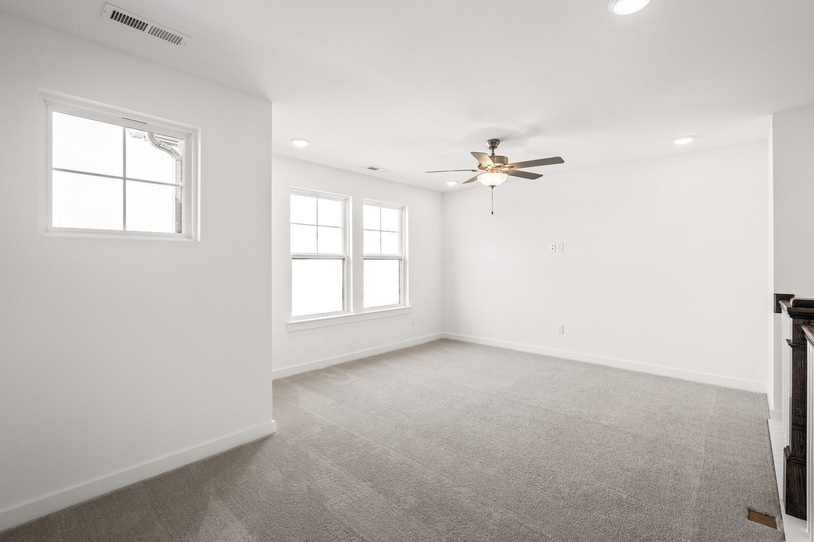 Bright upstairs loft with gray carpet, large double windows, bronze ceiling fan, and balcony railing in Davidson Homes Willow D, Mt. Juliet