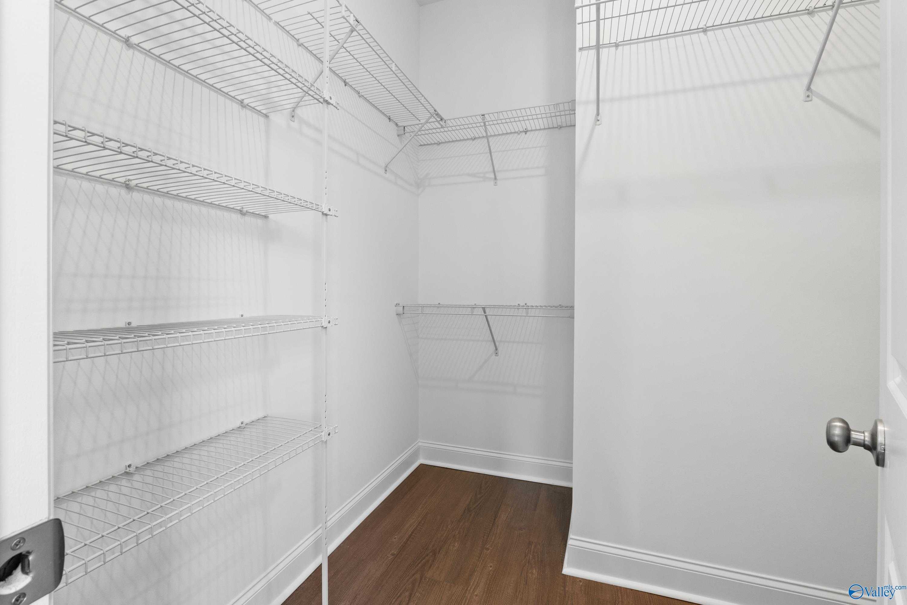 Spacious walk-in closet with wire shelving and hardwood floors in Evermore Homes The Haven, Owens Cross Roads, Alabama