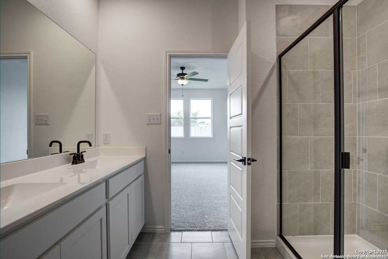 Modern master bathroom with double vanity, frameless glass shower, and bedroom view in Davidson Homes The Daphne H, Seguin TX
