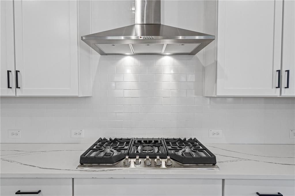 Modern kitchen with gas cooktop on white quartz countertop, shaker cabinets, subway tile backsplash in Davidson Homes The Edison A, Loganville, GA