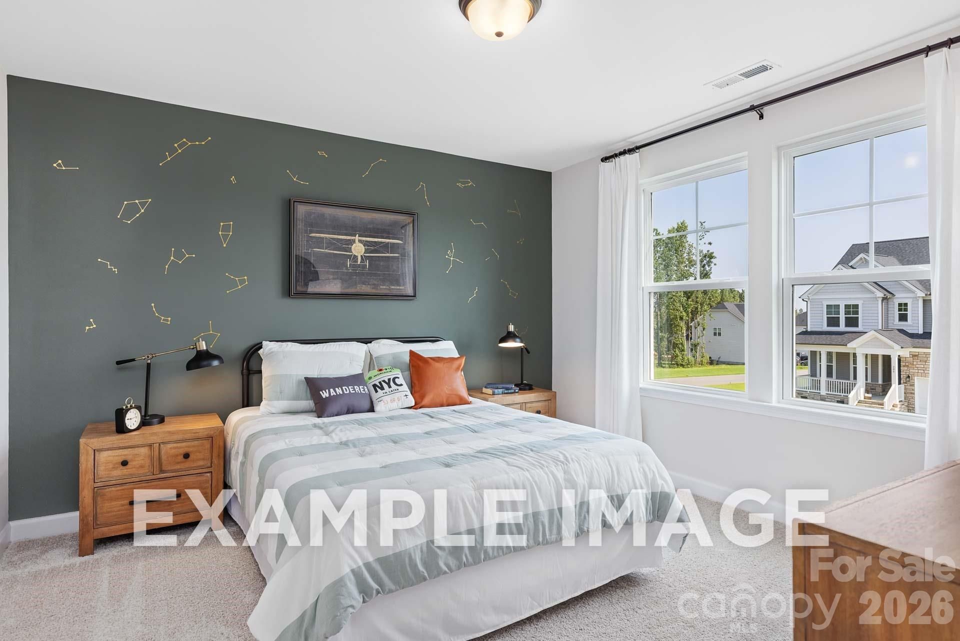 Cozy bedroom with sage green constellation accent wall, wood nightstands, and large windows in The Willow B, Windgate, Mooresville NC