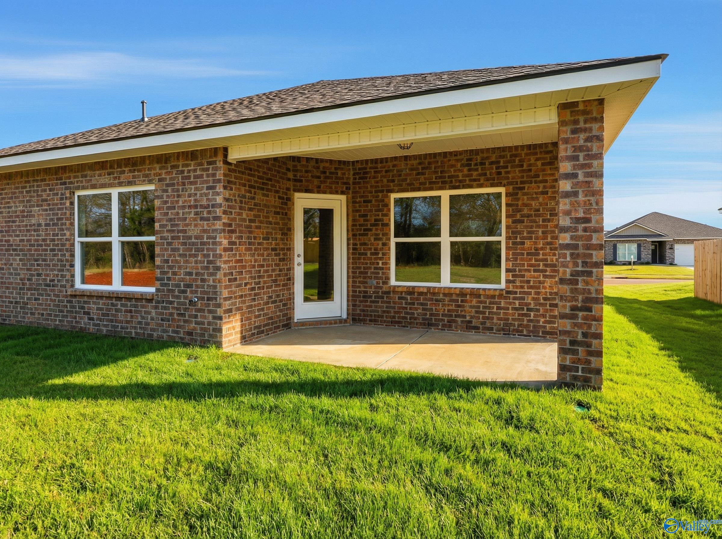 Single-story brick home with covered front porch, large windows, and lush green lawn in Lynn Meadows, Meridianville, Alabama