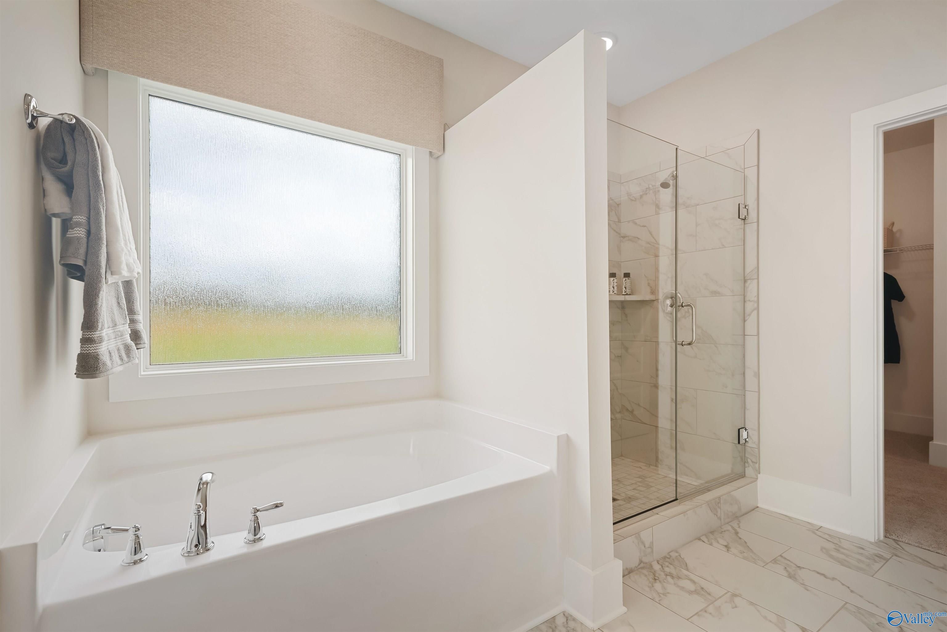 Luxurious master bathroom with freestanding tub, glass-enclosed shower, and large window in Davidson Homes The Everett, New Market, Alabama