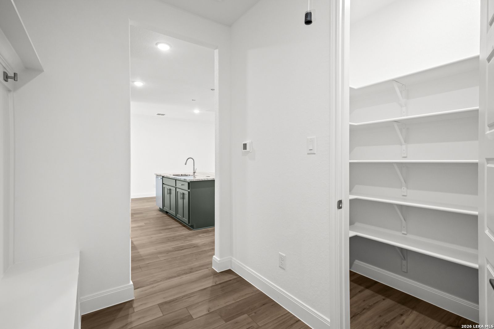 Walk-in pantry with white shelving adjacent to kitchen in The Lanier G floor plan at The Reserve at Potranco Oaks.