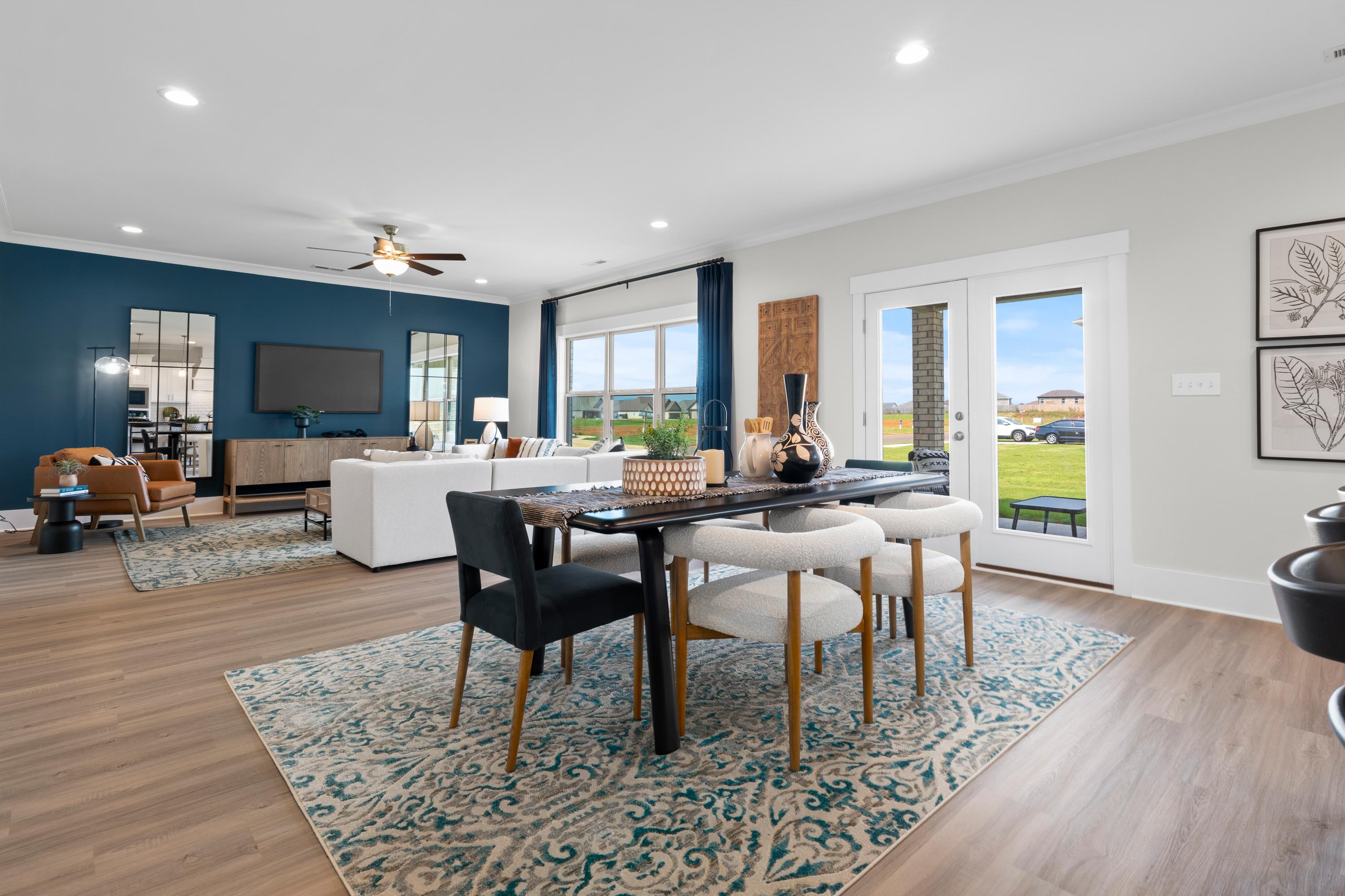 Open-concept living and dining area in The Chelsea A showcasing navy accent wall, white sofa, modern dining table, and sliding doors to lush backyard