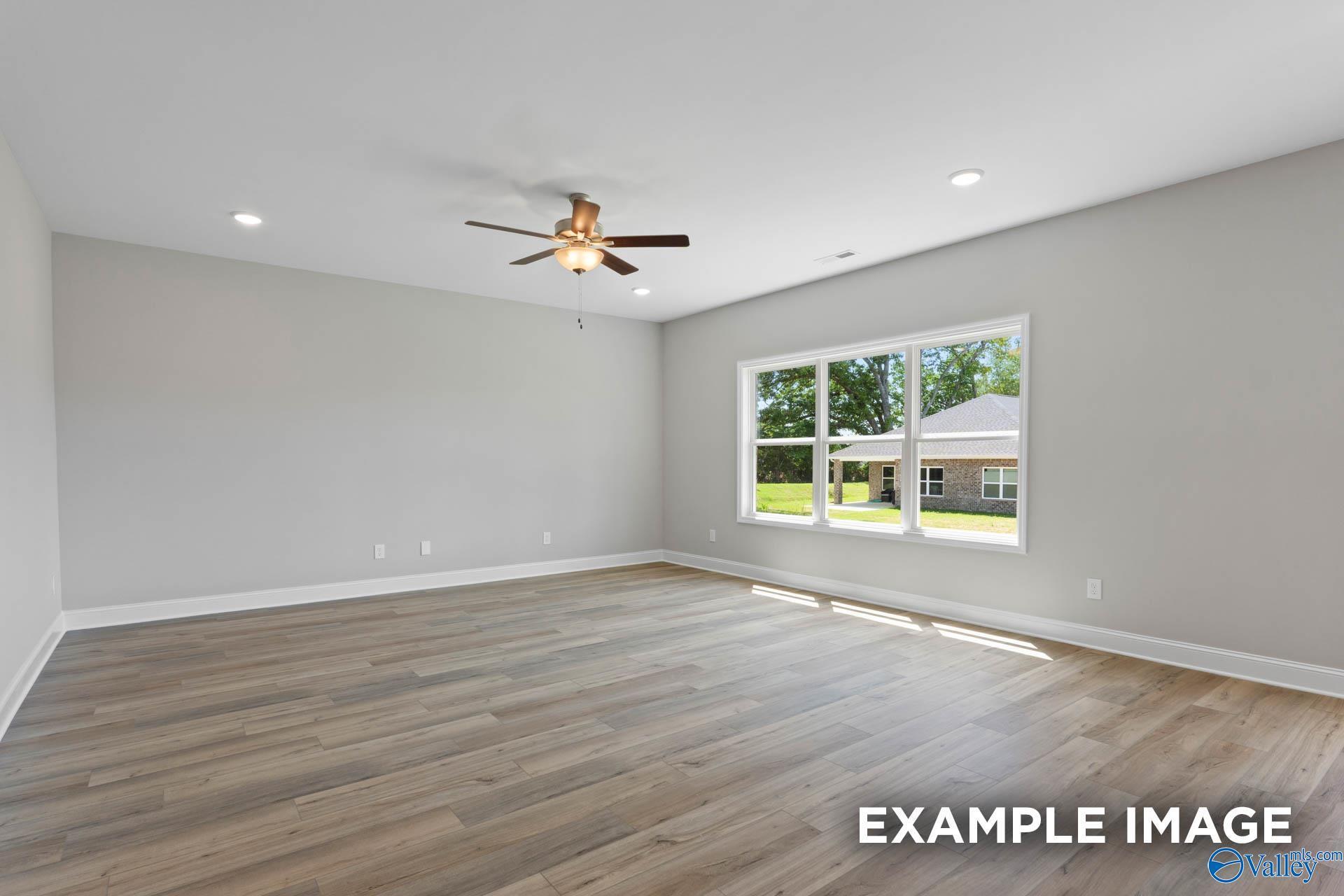 Spacious empty bedroom featuring gray walls, hardwood floors, ceiling fan, and large window with yard view in Davidson Homes Chelsea B, New Market AL