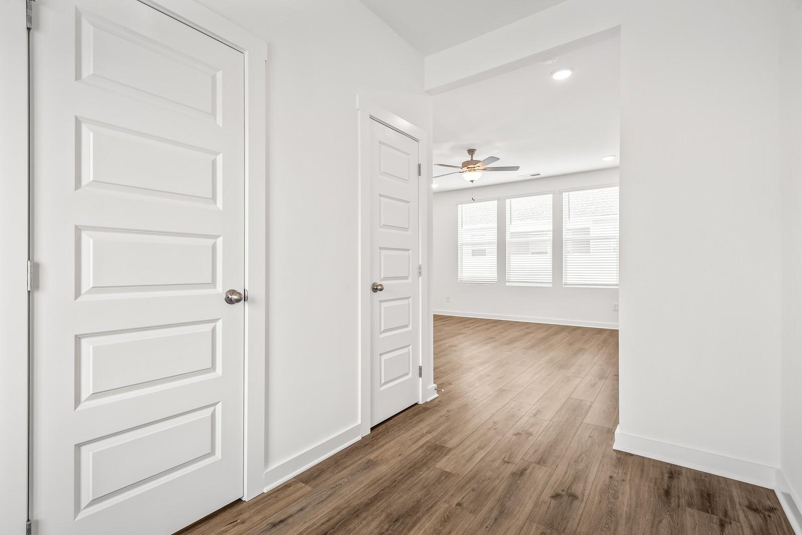 Bright hallway featuring white doors, hardwood floors, ceiling fan, and large windows in Davidson Homes The Gordon C, White House, Tennessee