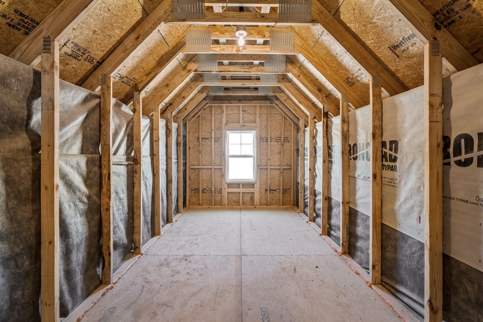 Unfinished bonus room with exposed wooden rafters, OSB panels, and window in Davidson Homes The Ash A, Gallatin, TN