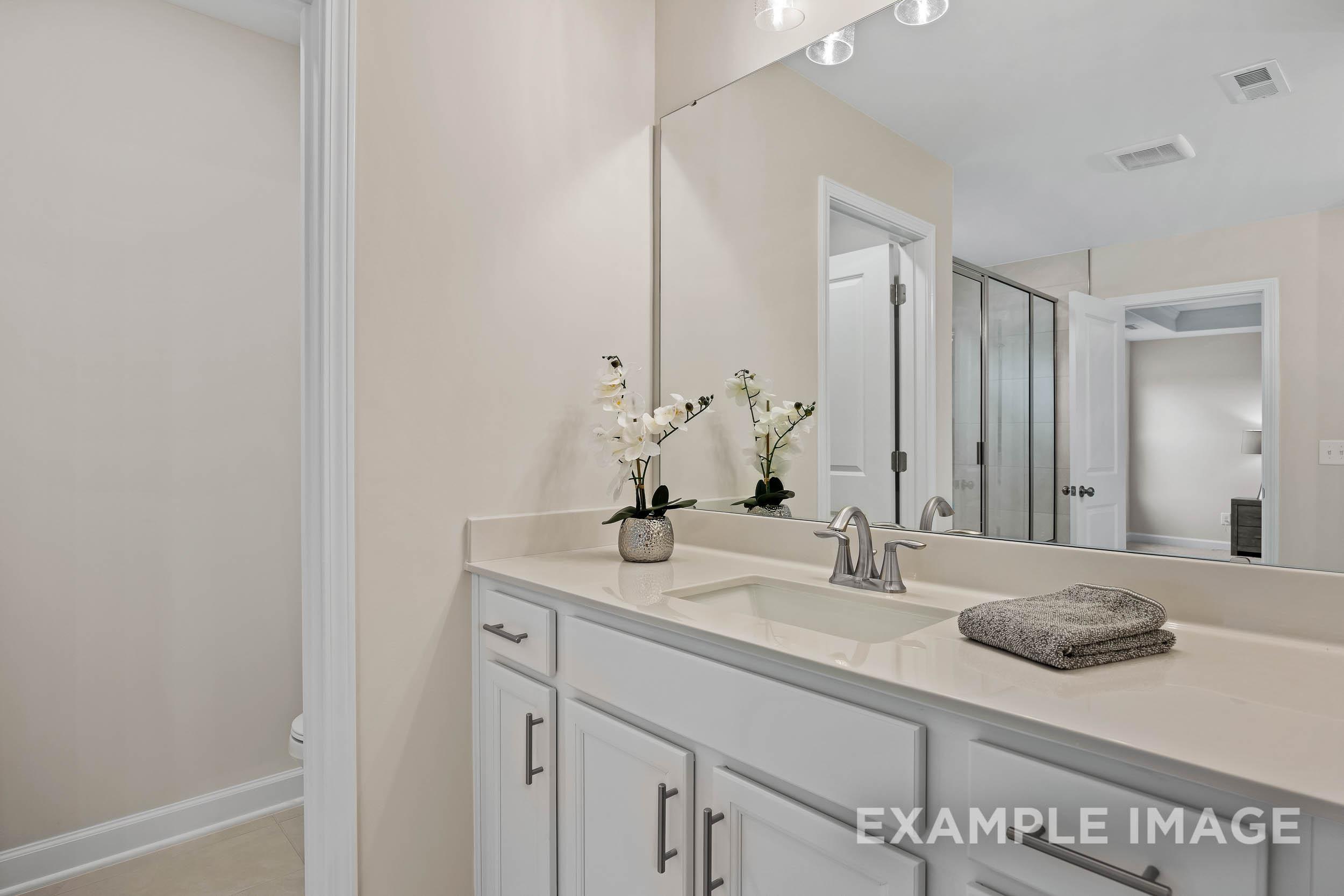 Spacious master bathroom in The Preston A with double vanity, large mirror, and glass shower enclosure