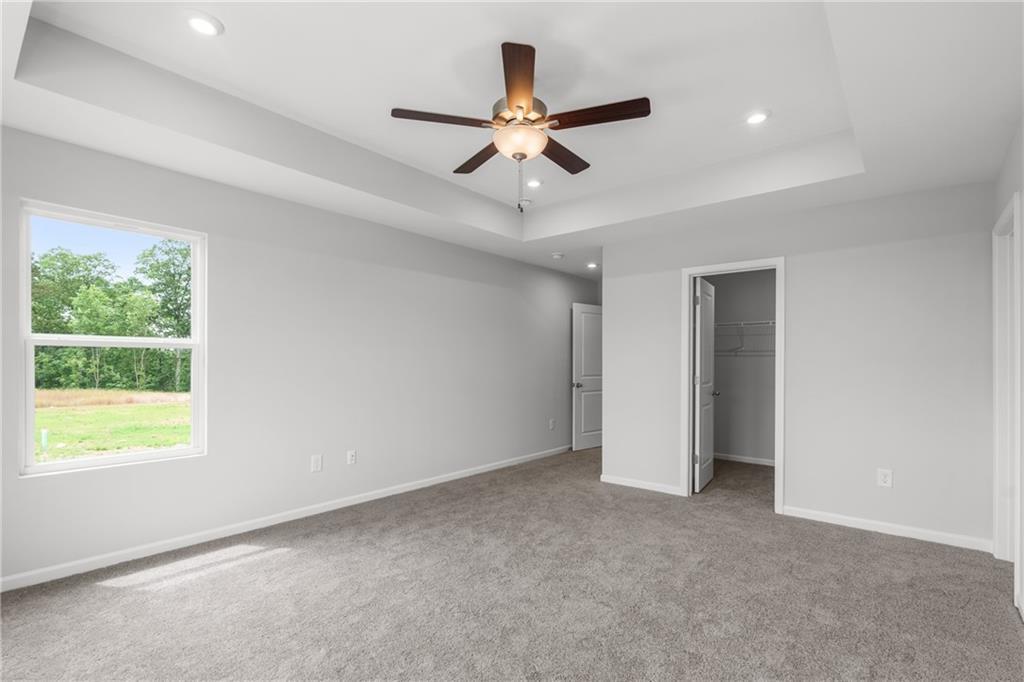 Spacious master bedroom with ceiling fan, large window overlooking wooded yard, open walk-in closet in The Monroe B, Emerson, Georgia