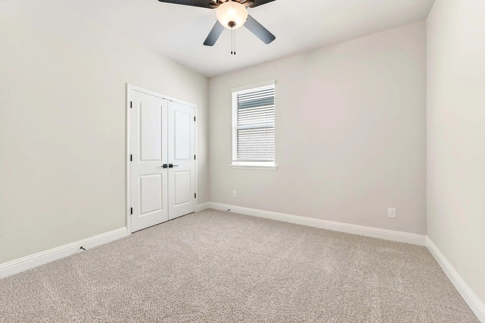 Bright bedroom with carpet, ceiling fan, and double-door closet in The Holly C floor plan by Davidson Homes in Heartland, TX