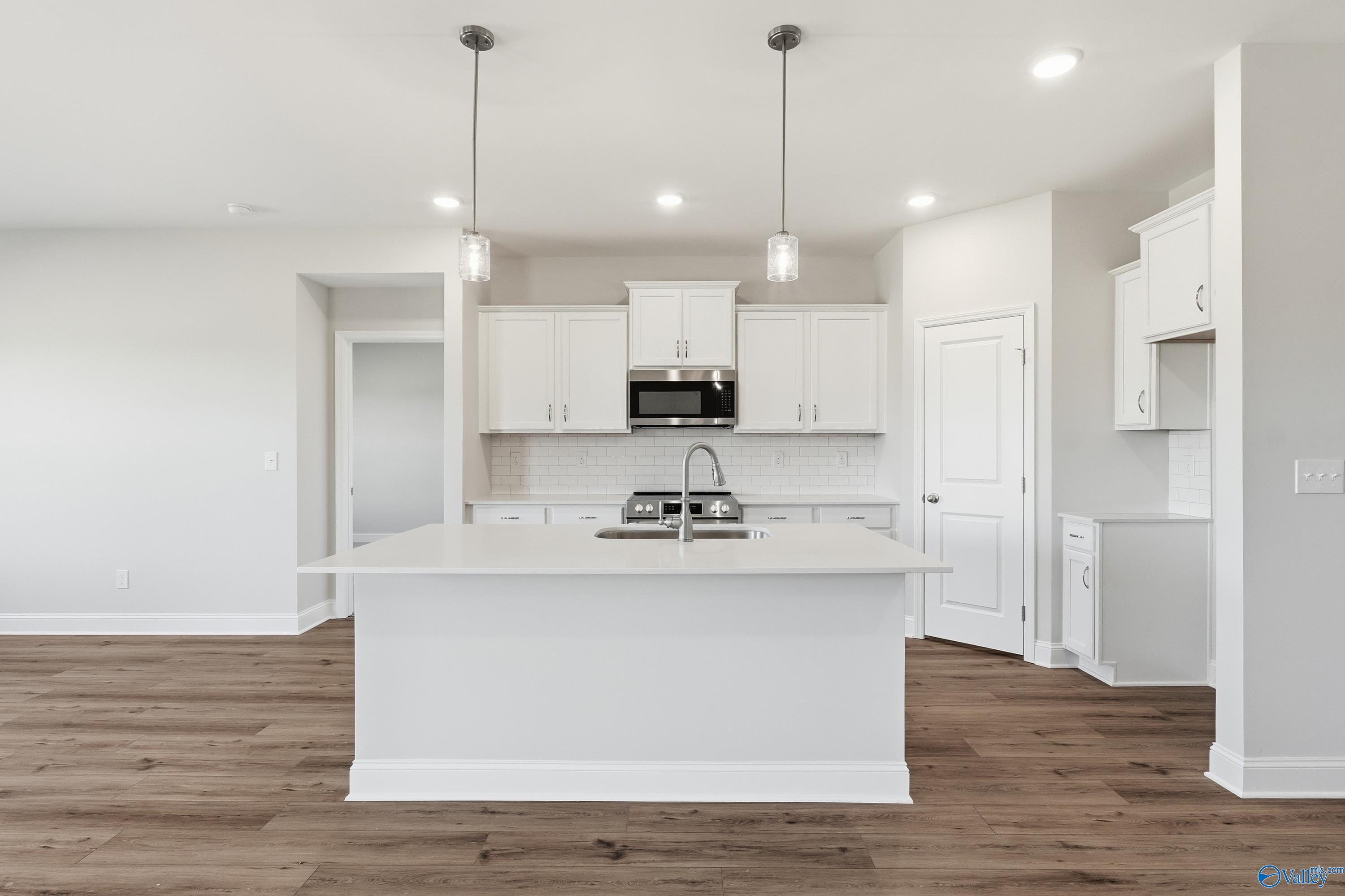 Bright open-concept kitchen with white shaker cabinets, quartz island sink, stainless appliances in Davidson Homes The Everett, Harvest AL