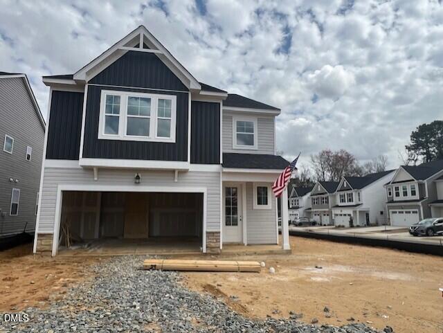 Modern 2-story Adalynn B home by Davidson Homes in Gregory Village, Lillington, NC, featuring black siding, open 2-car garage, and American flag