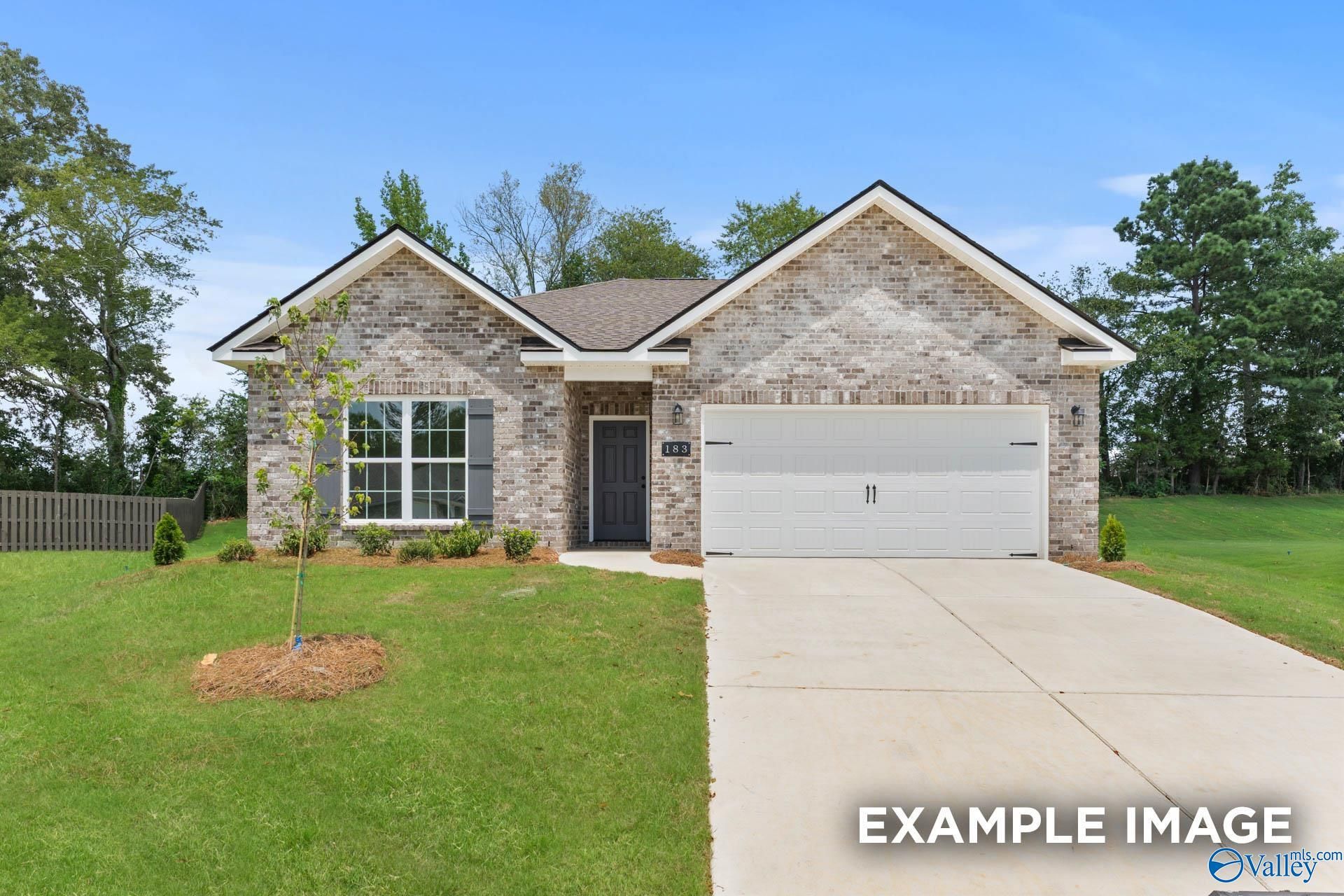 Modern single-story brick home with 2-car garage, lush lawn, and trees in Clearview, Hazel Green, Alabama - Davidson Homes Asheville C