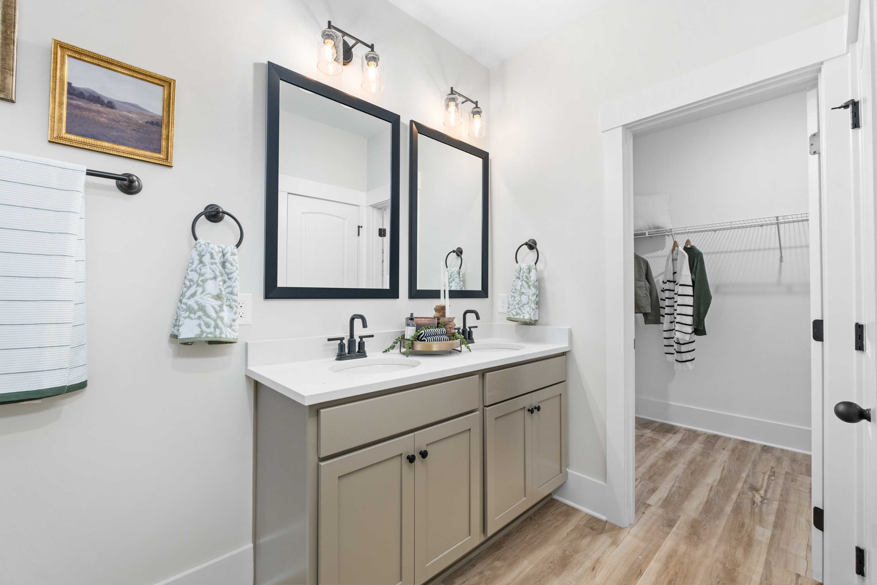 Spacious primary bathroom at Spragins Cove in Huntsville Alabama with double vanity, large mirrors, green towels, and walk-in closet