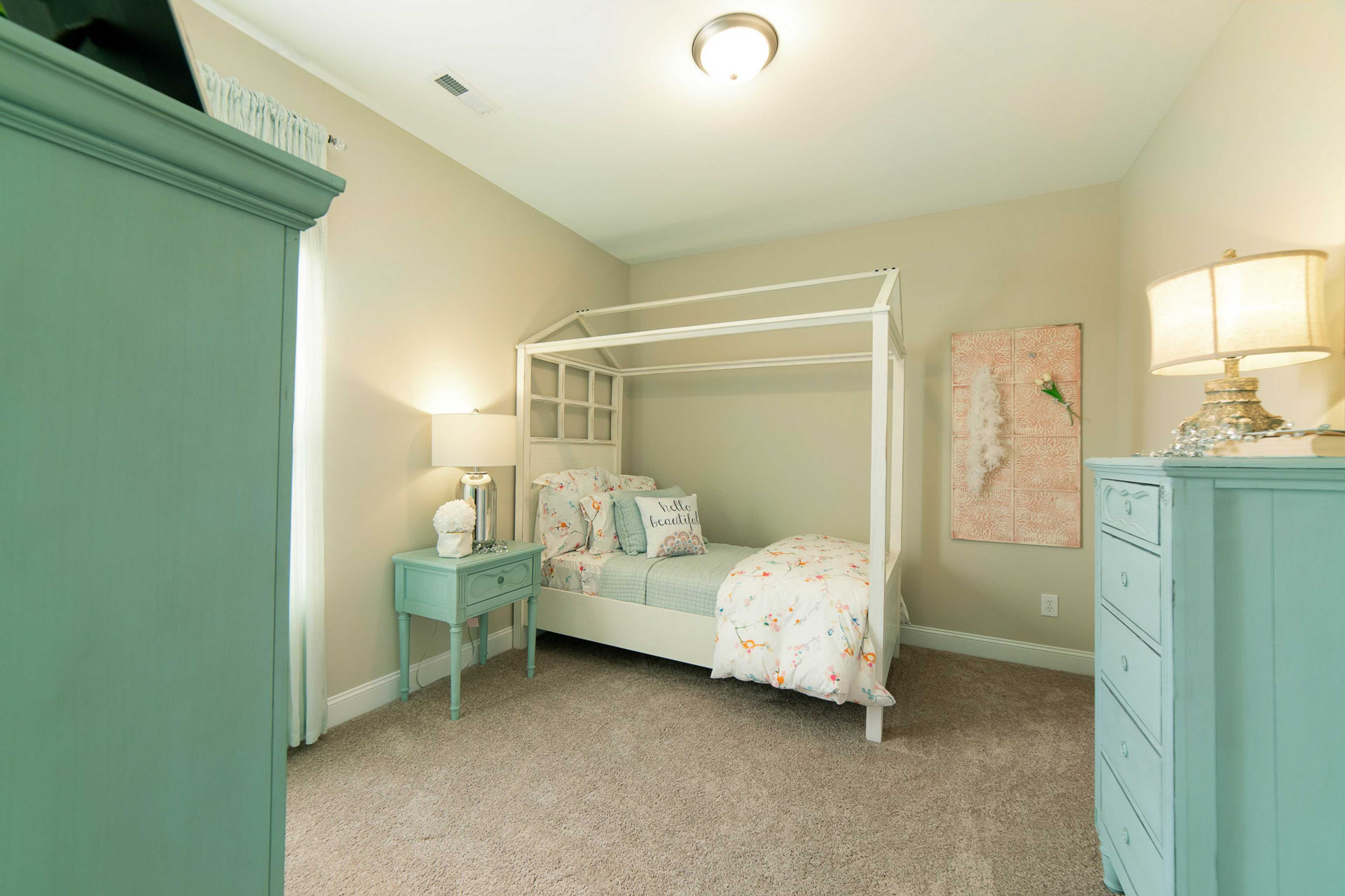 Cozy girl's bedroom with white canopy bed, floral bedding, and pastel furniture at The Dairy at Oak Grove in South Huntsville AL