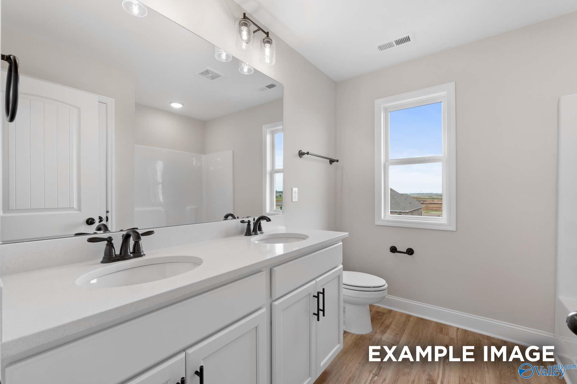 Modern bathroom with double vanity, quartz countertops, and dark fixtures in The Shelby B home at Jaguar Hills, Huntsville.